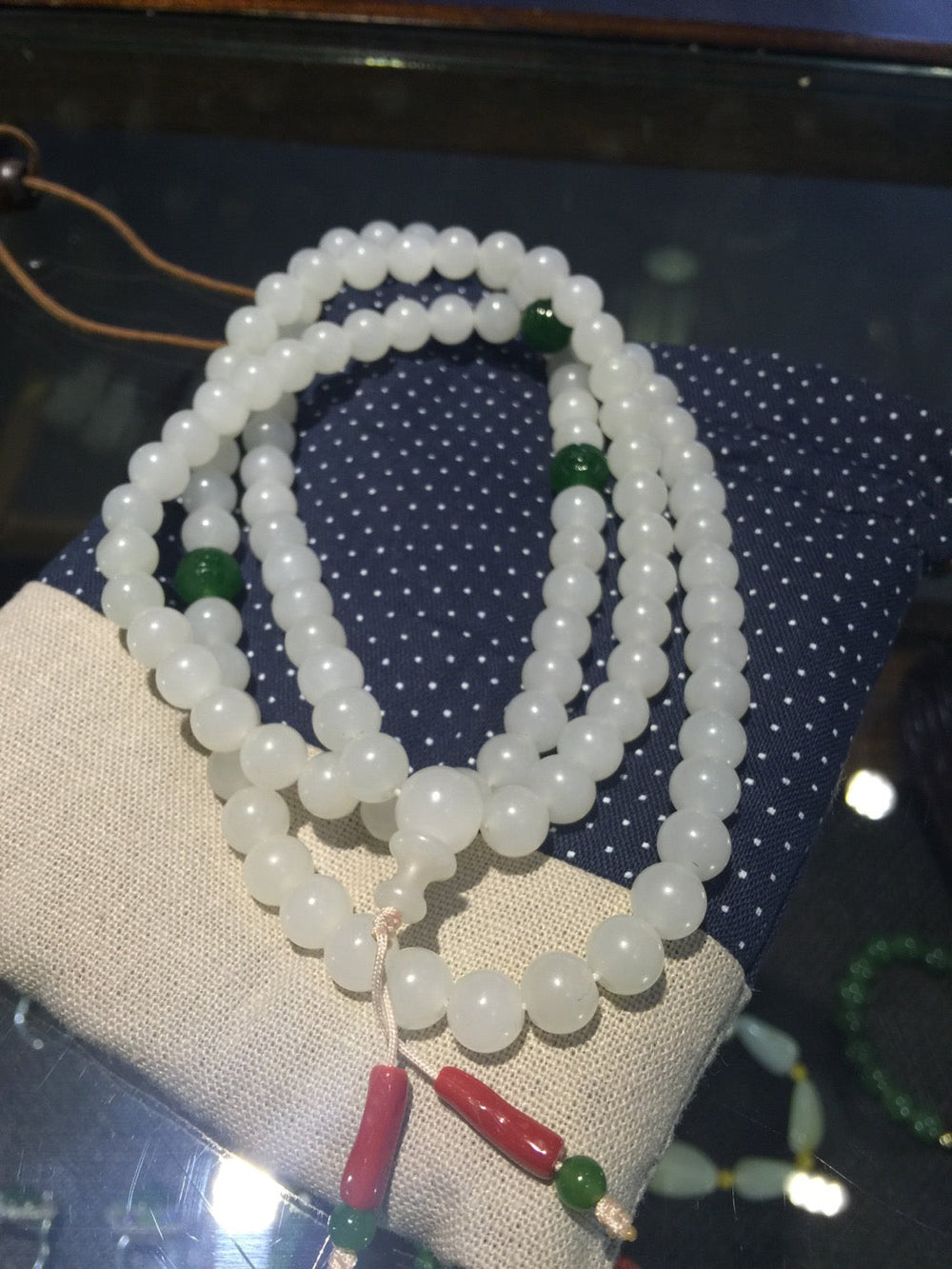 Pale round beads with green accents and red hanging ornaments