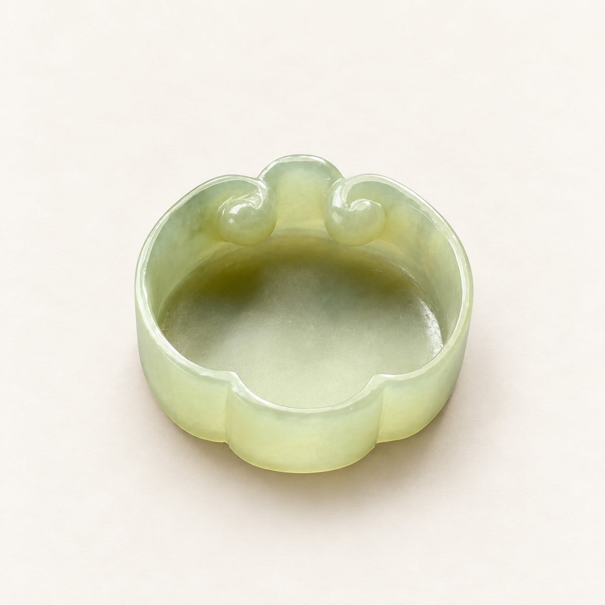 Pale green nephrite jade brush washer with curled ruyi details on a warm ivory background