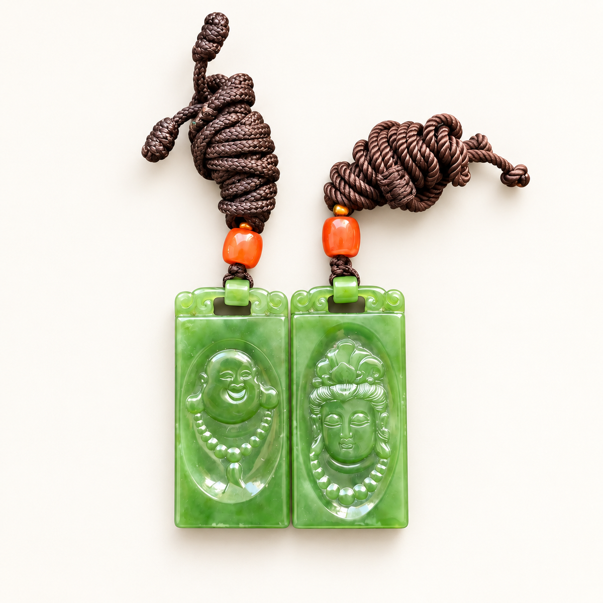 Matching green nephrite jade pendants carved with Guanyin and the Laughing Buddha, sold as a pair.