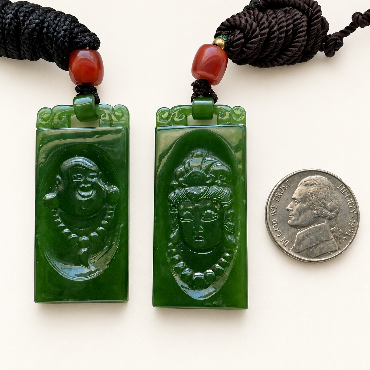 Green nephrite Guanyin and Laughing Buddha pendant pair beside a nickel for approximate scale; coin not included.