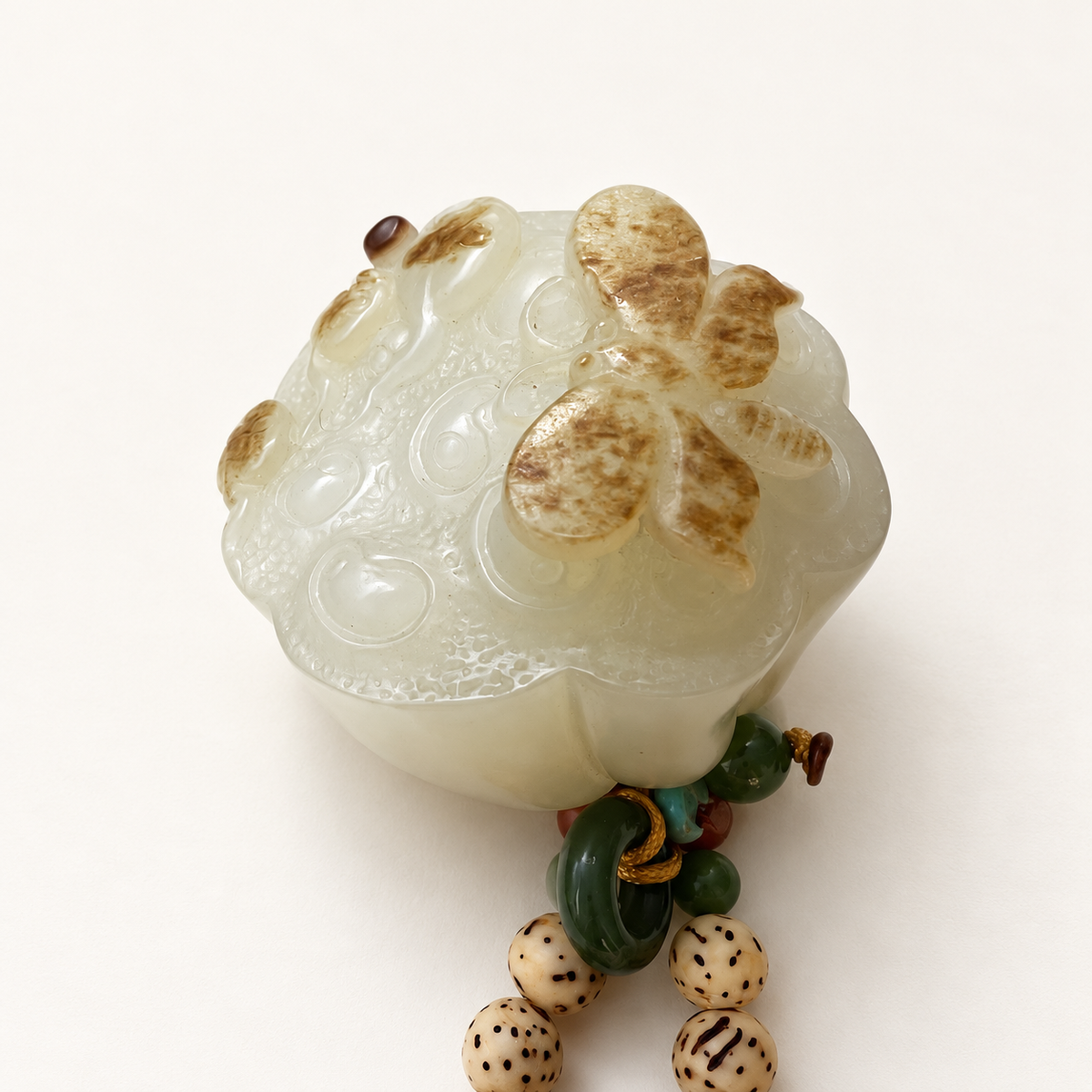 Nephrite lotus seedpod pendant with butterfly carved using natural brown skin coloration.