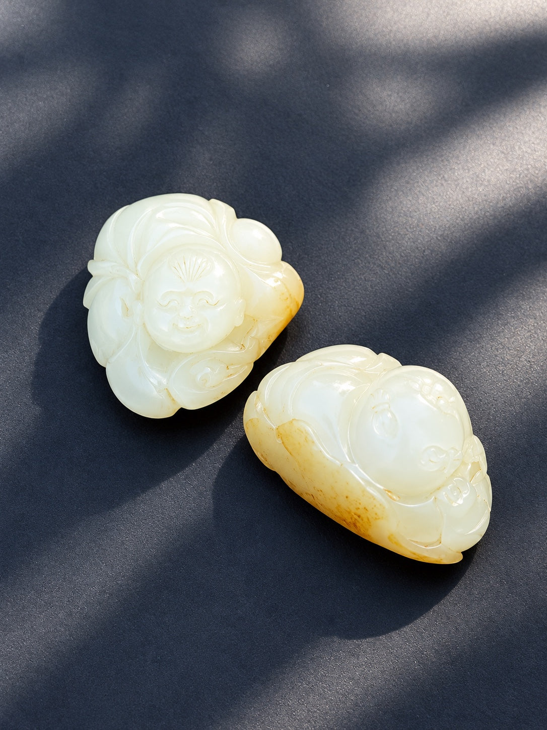 Angled view of two nephrite jade Hehe Immortals carvings sold together as a pair