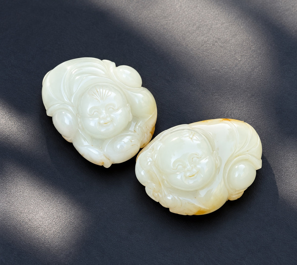 Pair of creamy white nephrite jade Hehe Immortals carvings with golden skin coloration