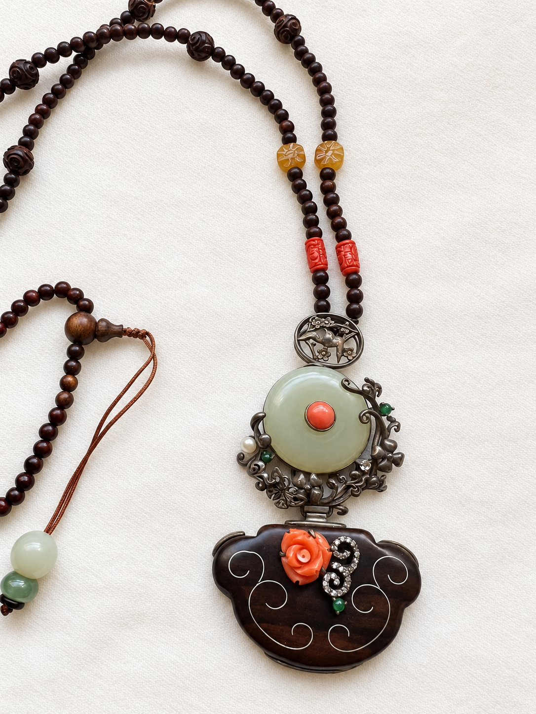 One-of-a-kind nephrite jade necklace with natural jadeite, red coral and 925 sterling silver details on ivory fabric