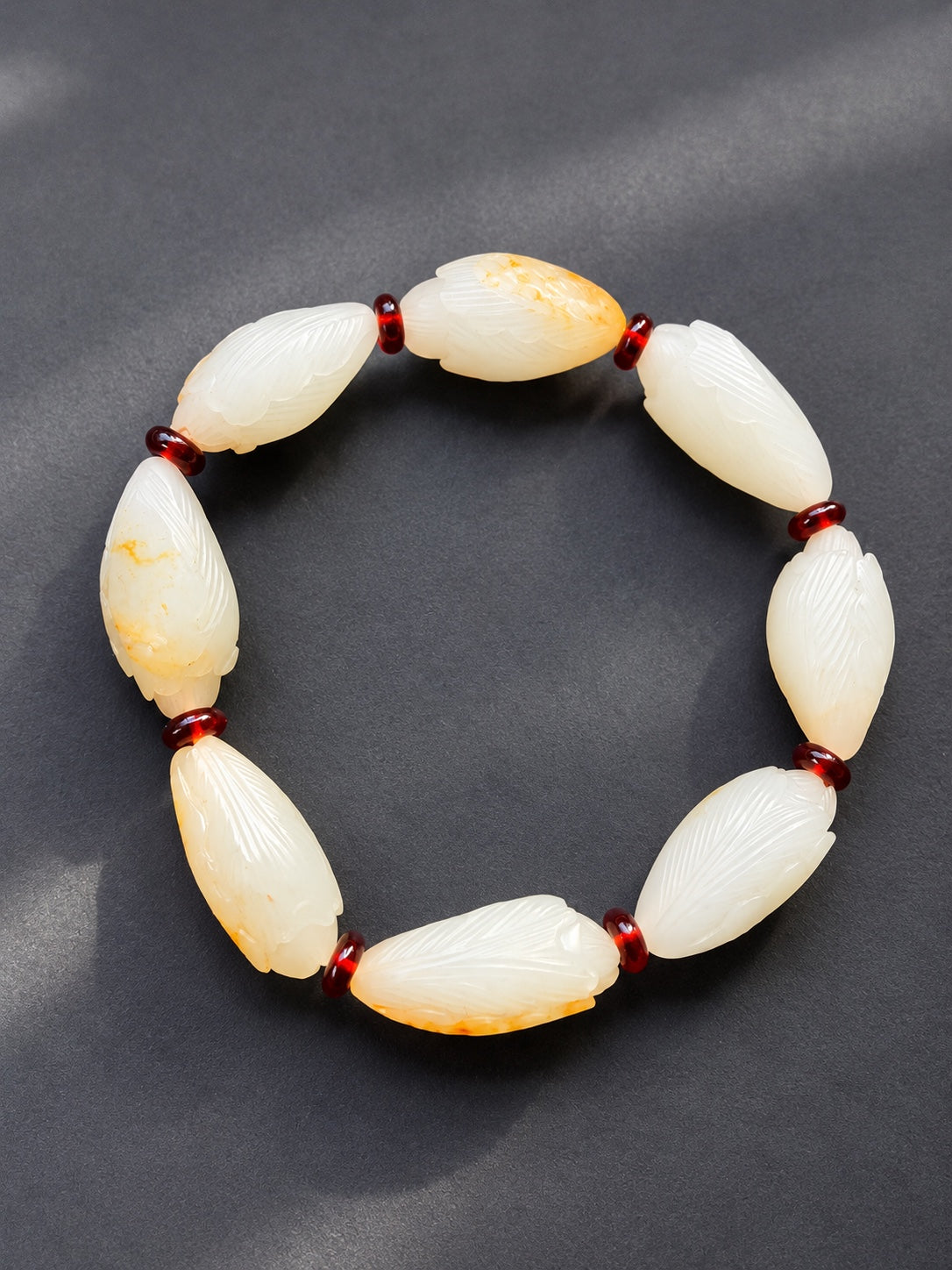 Full nephrite jade magnolia bud bracelet with natural golden skin on a dark gray background