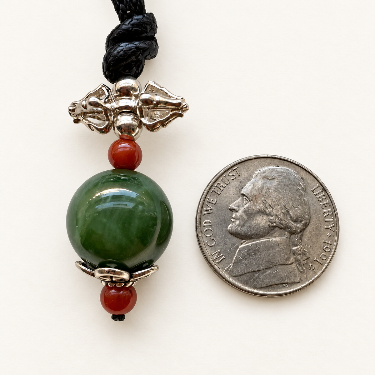 Nephrite jade vajra pendant beside a nickel for approximate scale; coin not included.