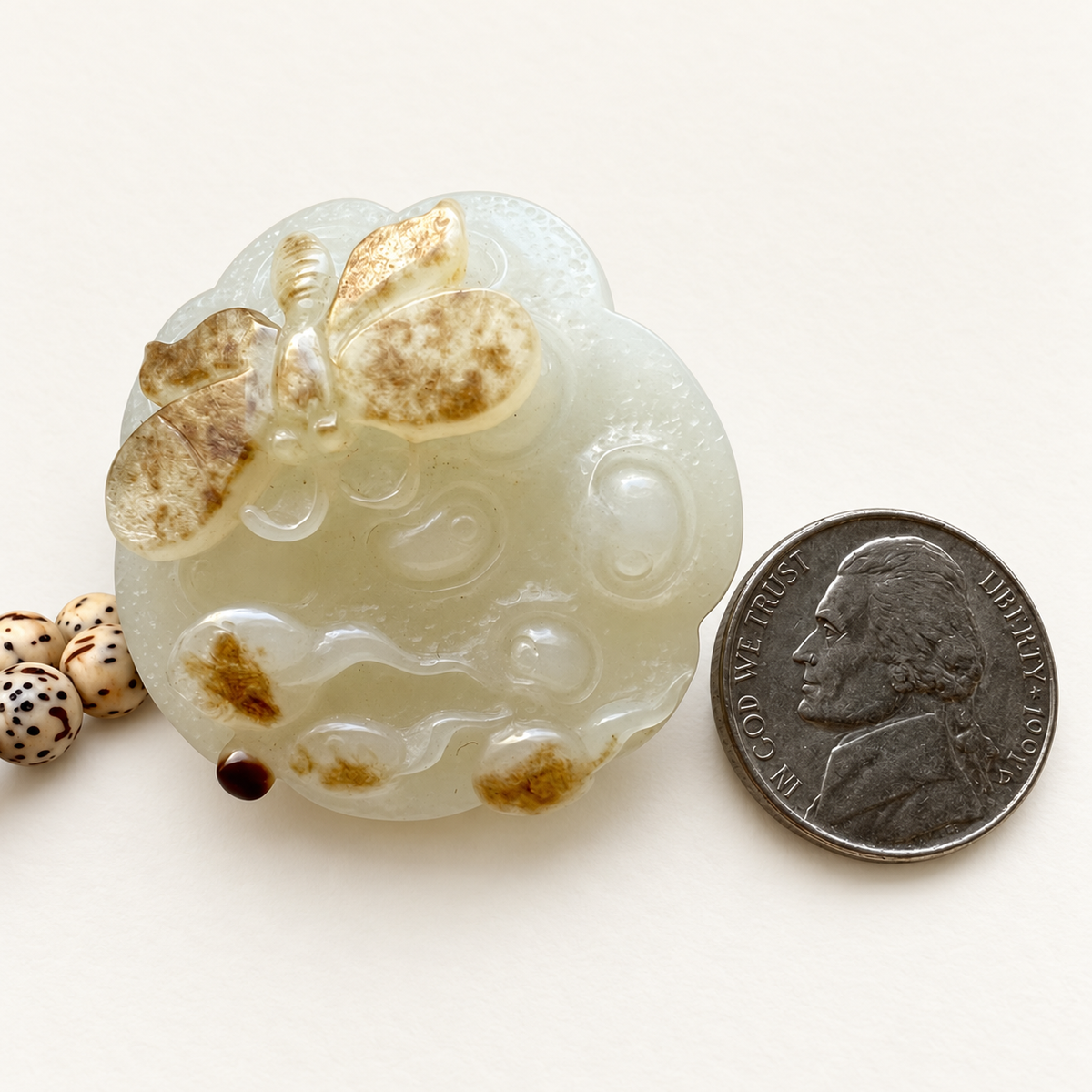Lotus and butterfly nephrite pendant beside a US nickel for approximate scale; coin not included.