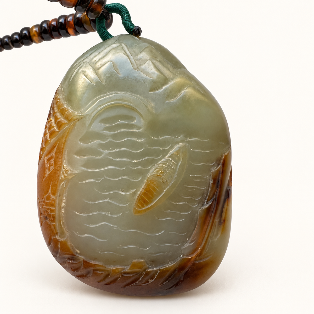 Angled front view of the tricolor nephrite landscape carving, showing mountains, river and boat.