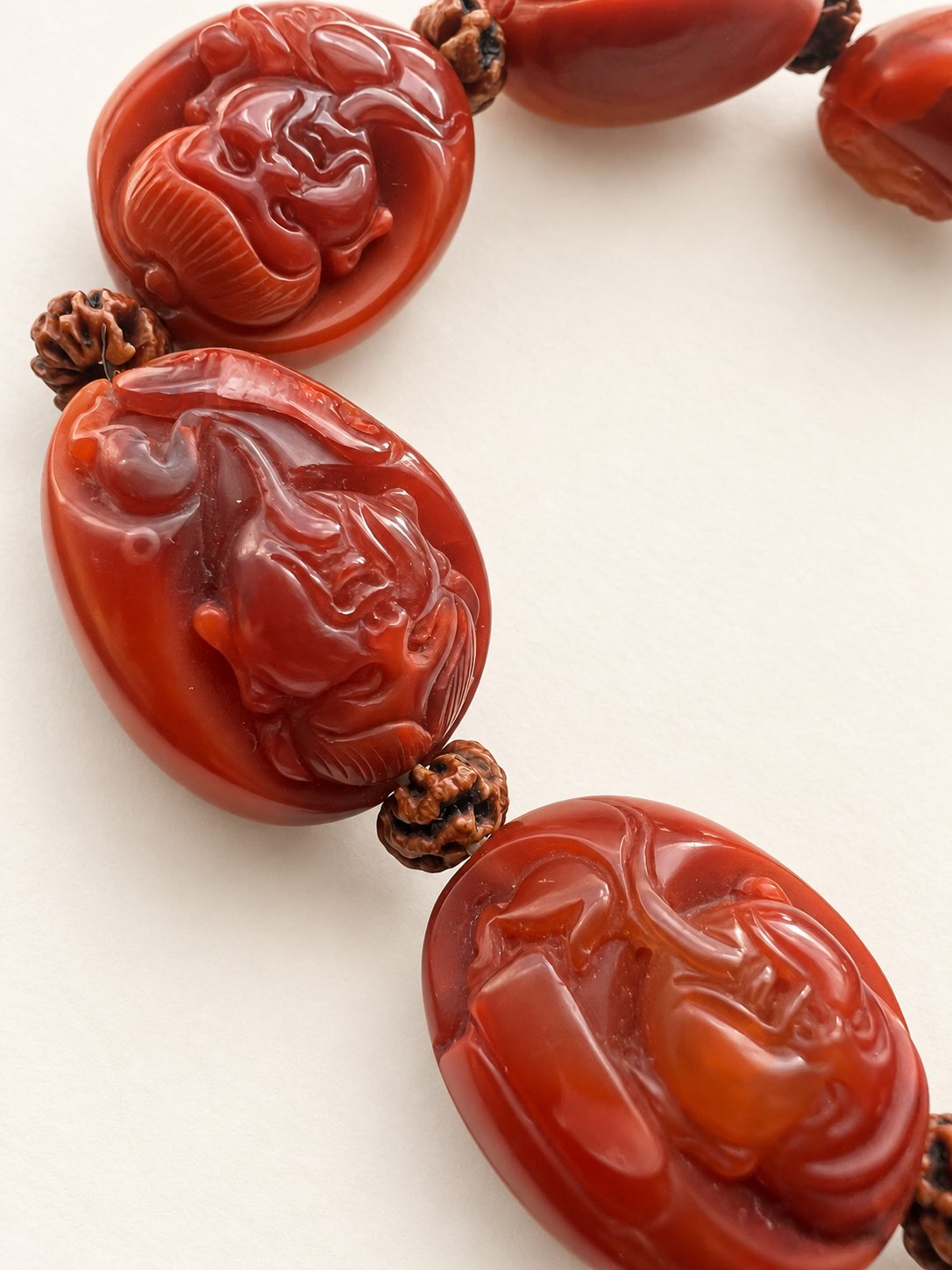 Close-up of Nanhong agate Eight Immortals carvings and bodhi seed spacers on warm ivory