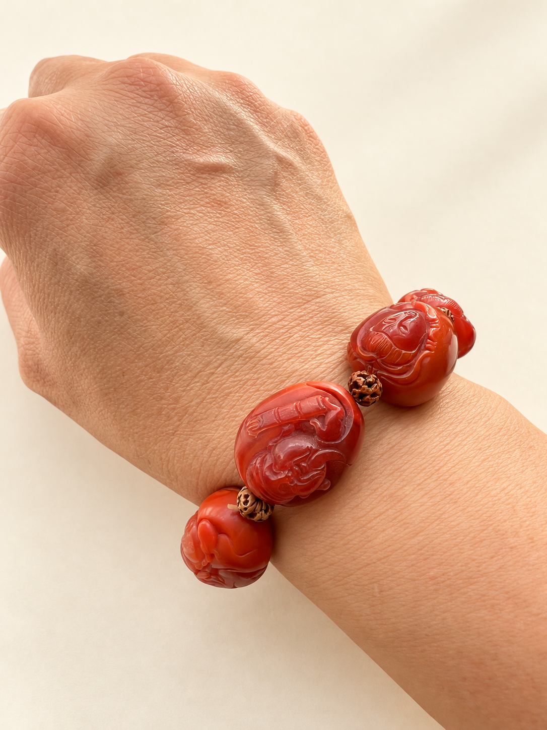 Nanhong agate Eight Immortals bracelet worn on a wrist against a warm ivory background