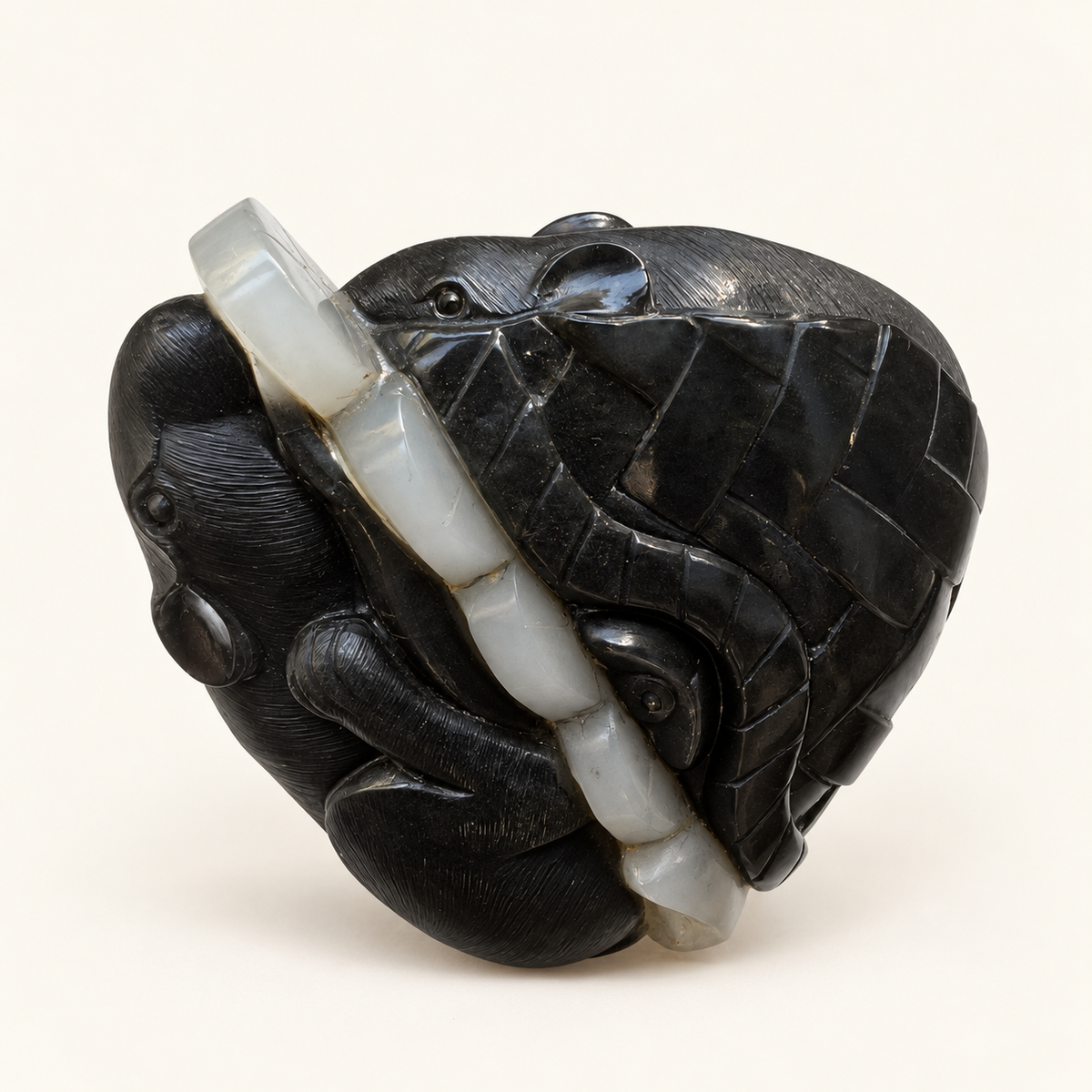Retouched side view of the black and white nephrite mice and coin pouch carving on a warm ivory background