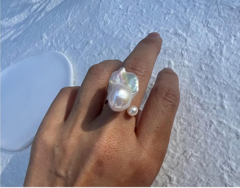 A finished Baroque pearl ring worn on a hand.